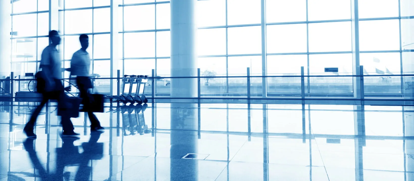 Men walking through an airport terminal carrying luggage and bags