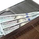 Article: Best Long Wallets for Guys. Image shows Hundred dollar bills in long wallet