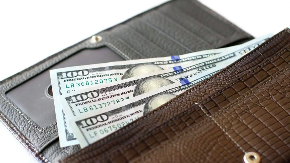 Article: Best Long Wallets for Guys. Image shows Hundred dollar bills in long wallet