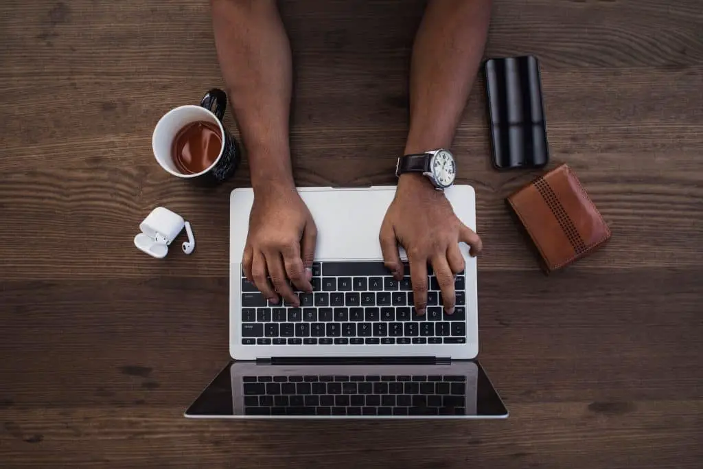 may typing on laptop with coffee and wallet