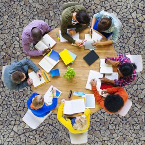 People Sitting Around A Table Studying or Desiging