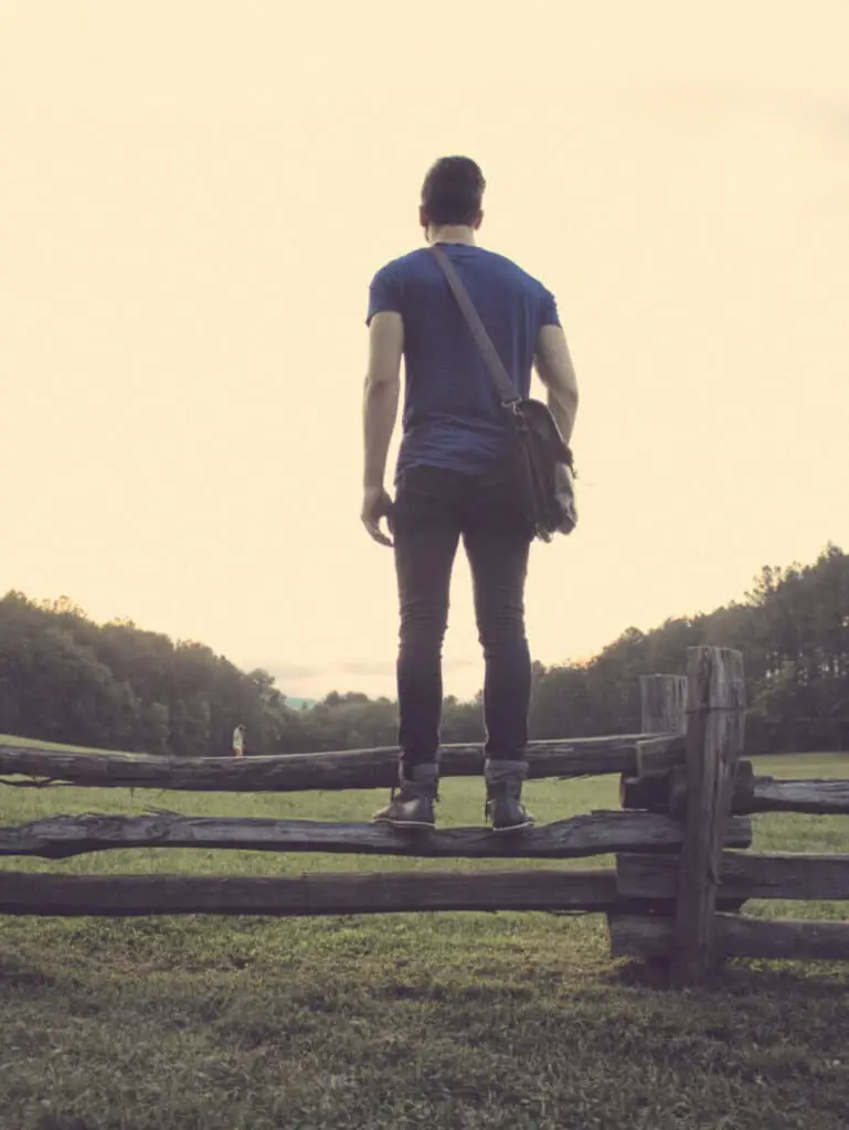 man on fence with messenger bag