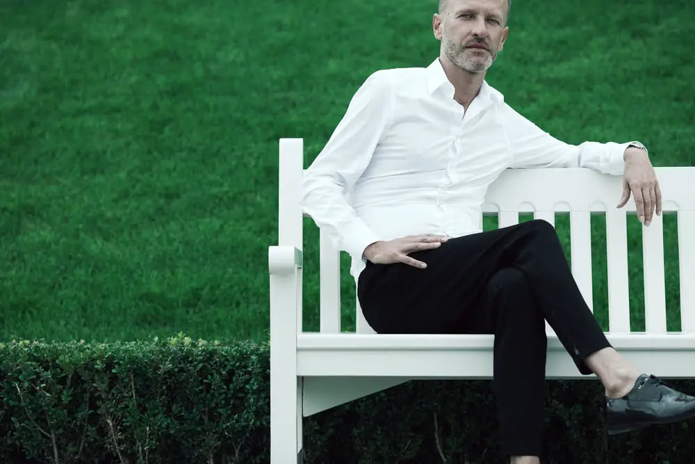 Article: What Colors Go With Black Clothes? Image shows man on bench in black pants and white shirt