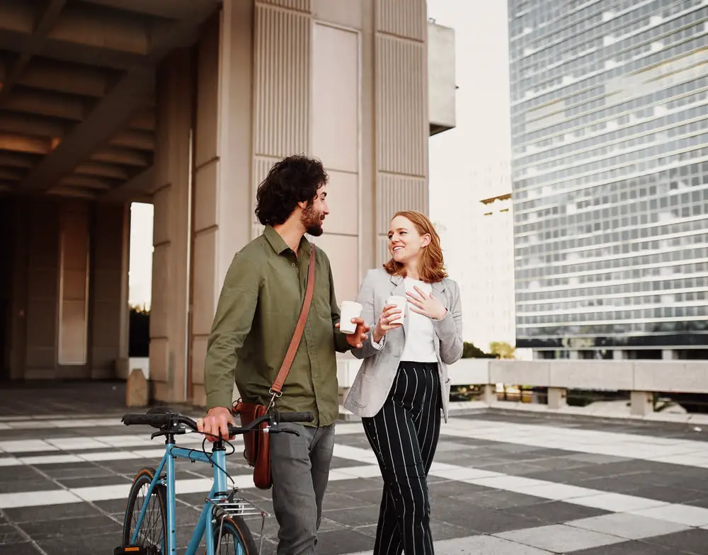 Image shows a couple walking, the man wearing a messenger style crossbody bag