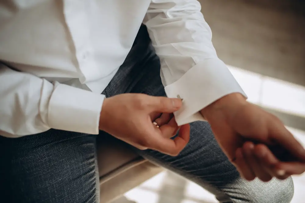 Man fitting cufflink into French double cuff shirt