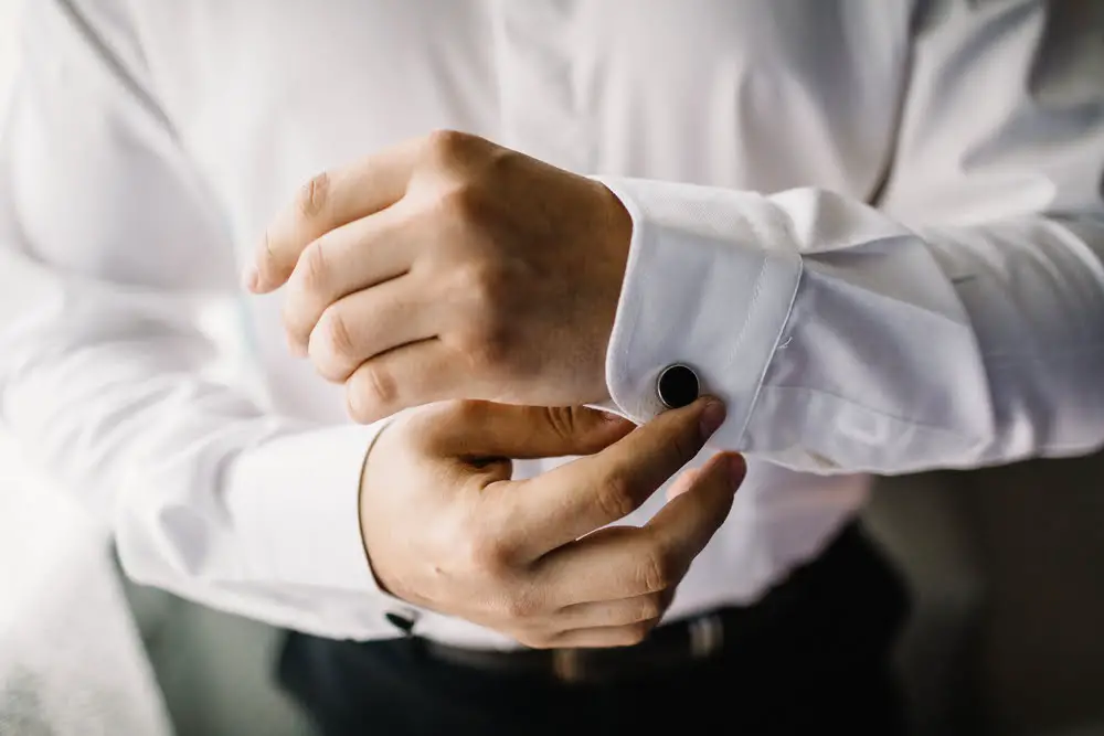 Man fitting cufflink into single cuff shirt