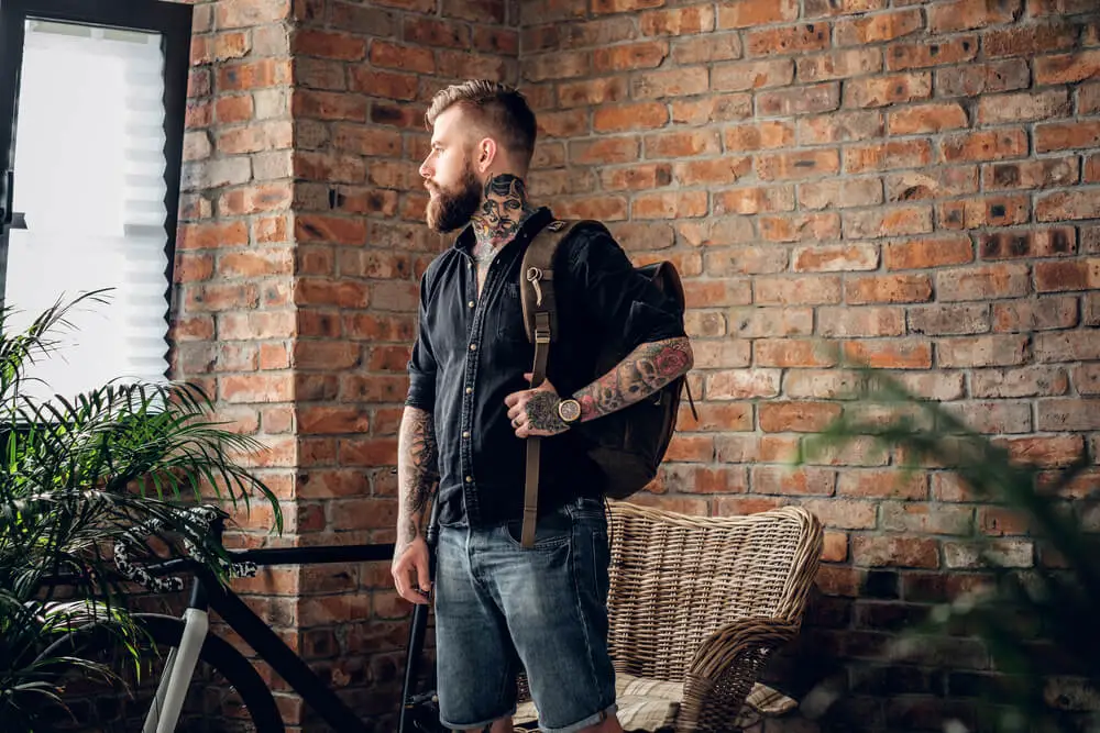 tattooed hipster with leather backpack